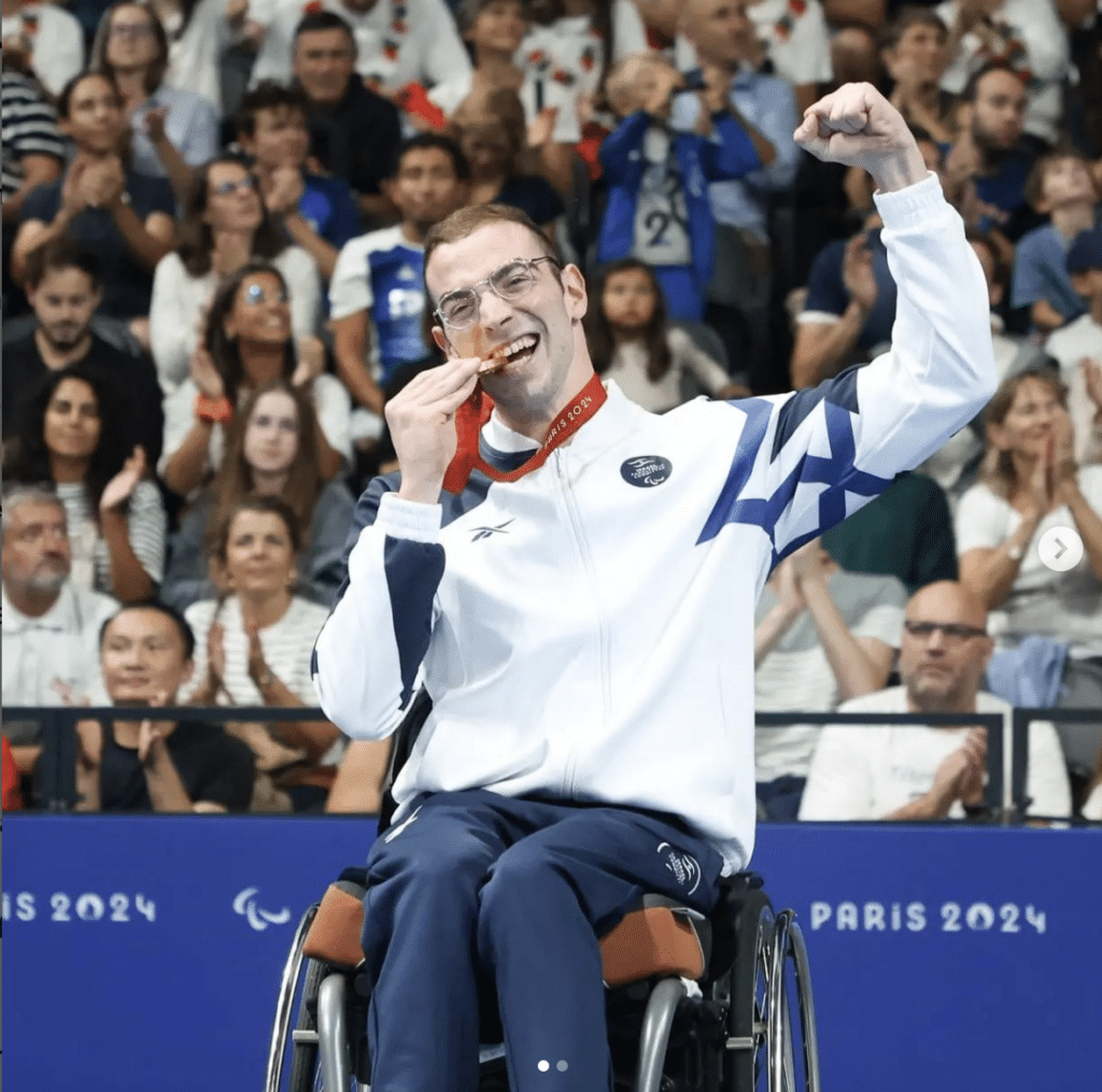 Ami Dadaon biting his gold medal (Instagram // @Israelswimming)